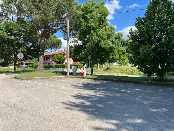 Parcheggio di Sant'Arcangelo con strisce bianche, delimitato da alberi, vicino a zona residenziale tranquilla.